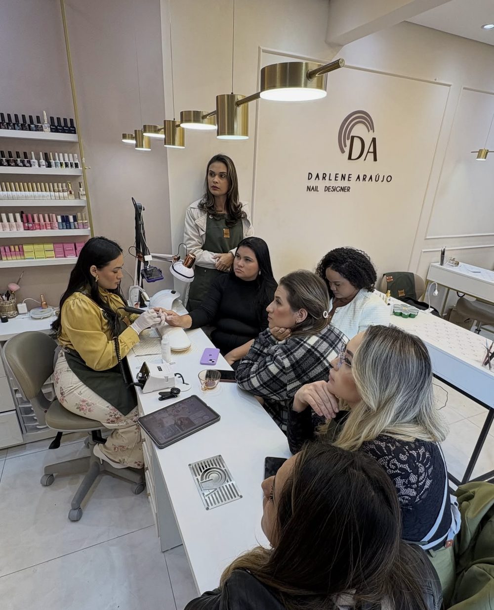 Alunas em volta da mesa enquanto a Darlene demonstra a técnica