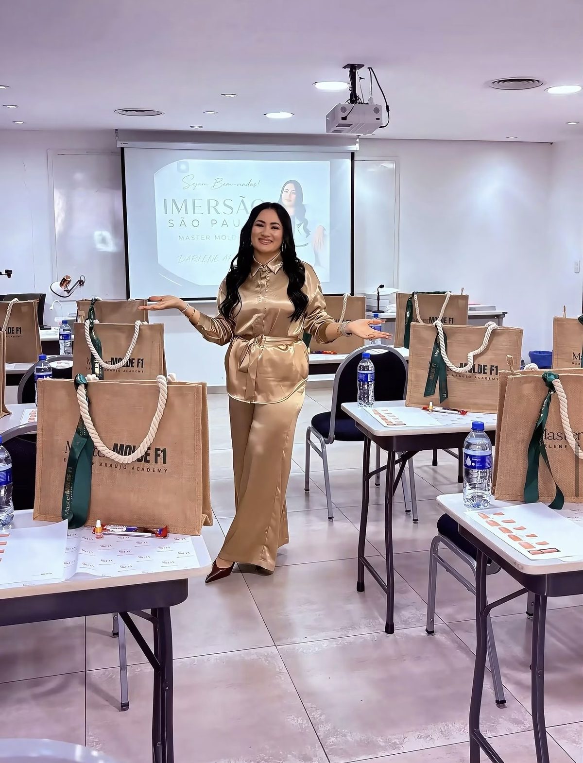Darlene na sala da Imersão São Paulo, com as bolsas Molde F1 das alunas nas mesas